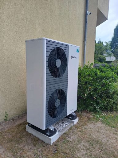 Vaillant Wärmepumpe mit zwei Ventilatoren auf einem Platz neben einem Gebäude.