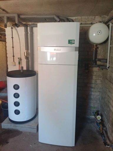 Inneneinheit Wärmepumpe neben einem Wasserboiler in einem Keller.